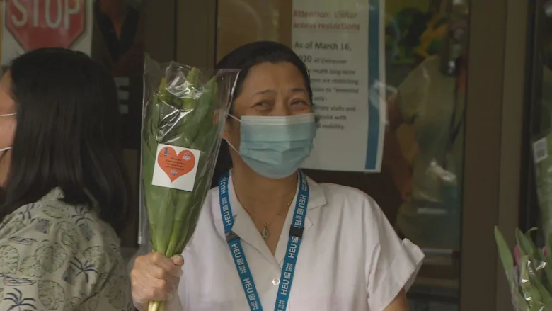 A frontline worker at the Haro Park Centre in Vancouver's West End receives a bouquet of tulips.